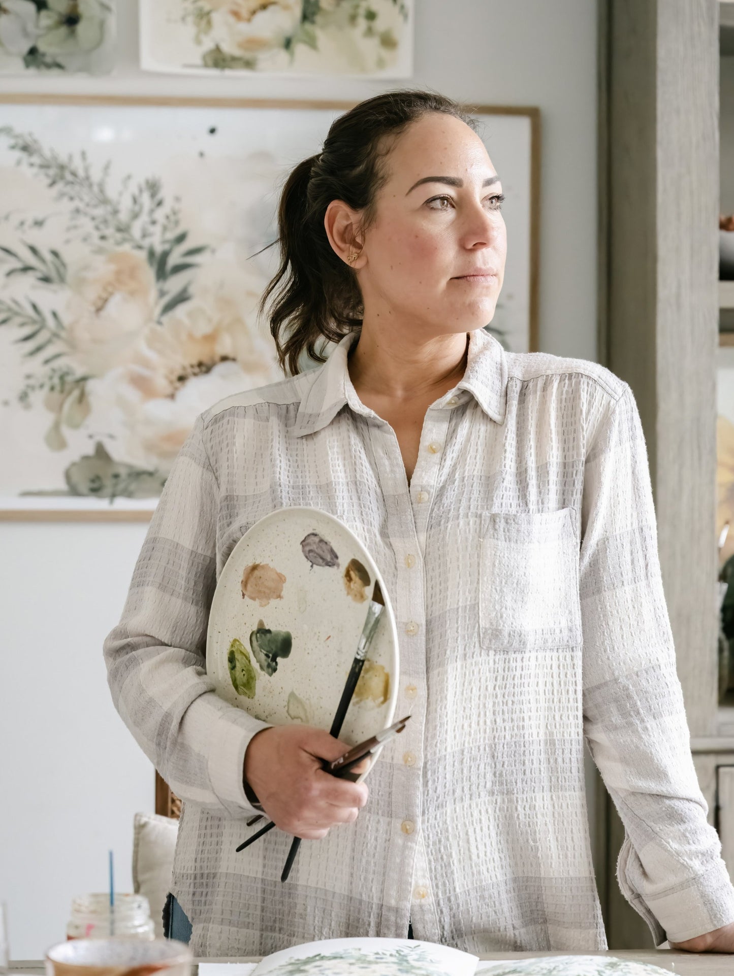 Artist Tonya Cruz in studio holding watercolour paint palette