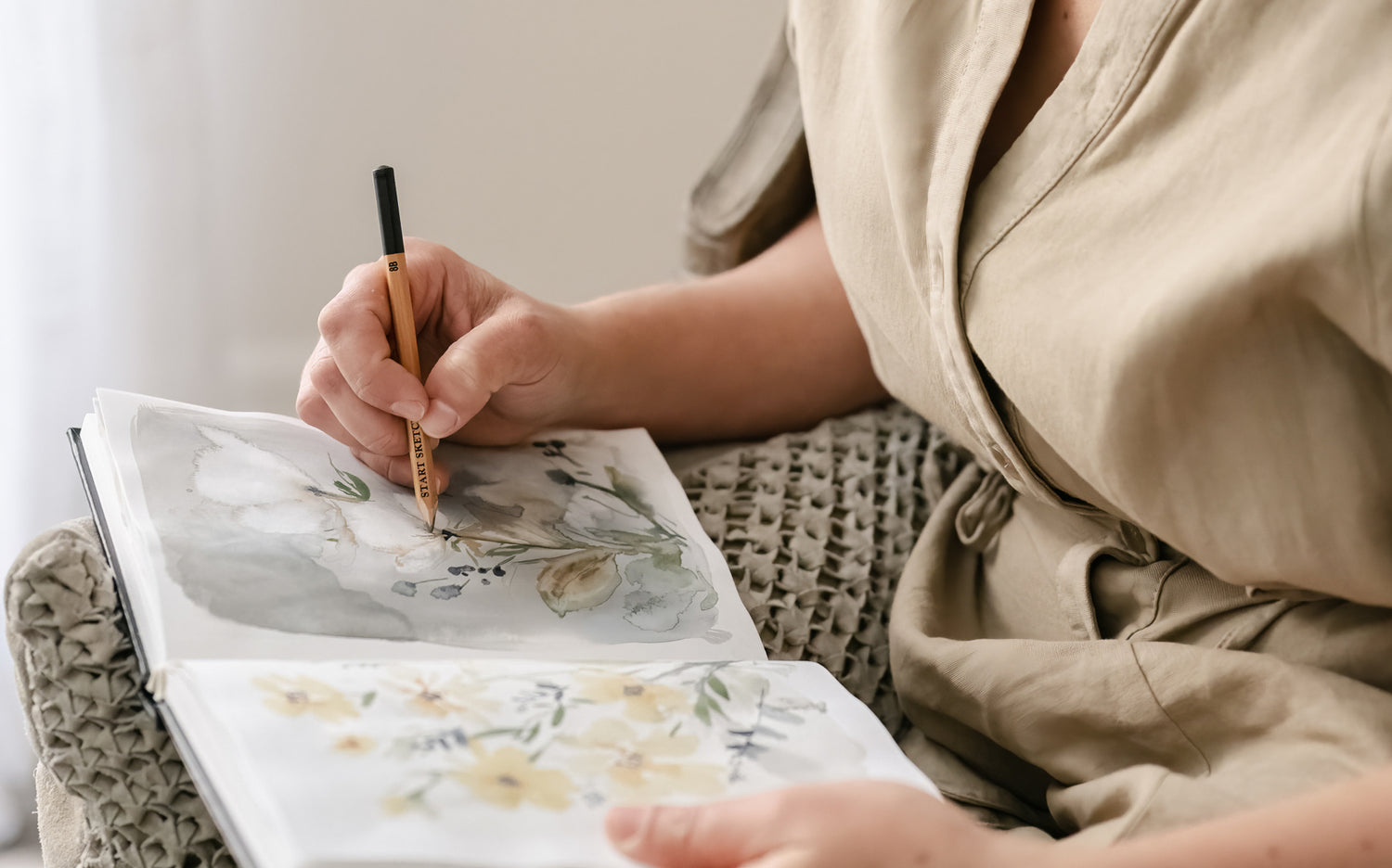 Artist Tonya Cruz sketching flowers in sketch book, close up shot